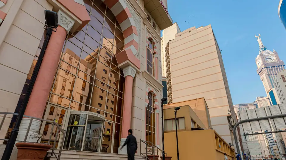 واجهة فندق ضيافة الرجاء في مكة المكرمة، وبرج الساعة في البعيد